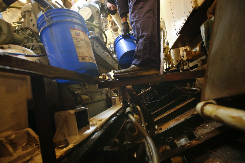 Windward Power Systems technician Jack Benway drains the existing coolant fluid aboard the fishing boat Fisherman which has just had a new engine installed.  After four months out of order, the New Bedford, MA fishing boat is expecting to be running again by next week.  PHOTO PETER PEREIRA