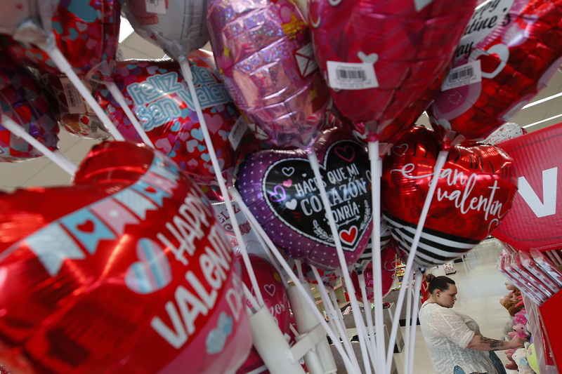 Colorful Valentine's Day balloons are seen in the foreground as a woman picks some stuffed animal gifts at Walgreen's in New Bedford, MA.  PHOTO PETER PEREIRA