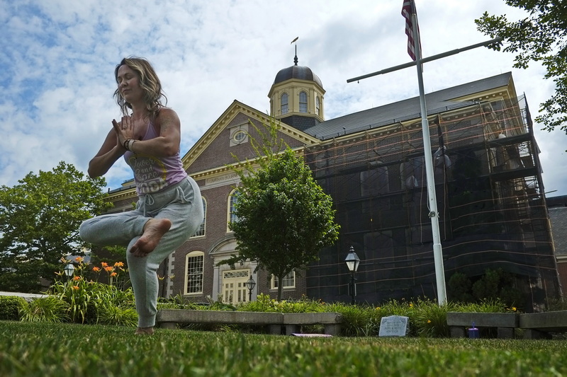 The Whaling Museum is seen in the background as Andrea DeVeau Cabral of Power and Grace Yoga is surrounded by history as she instructs a yoga class on the grounds of the Seamen's Bethel in downtown New Bedford, MA. The Awaken Yoga Flow sessions happen twice a week.  PHOTO PETER PEREIRA