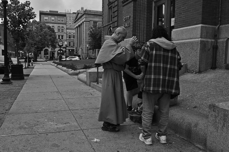 A Franciscan friar from Our Lady's Chapel in New Bedford, prays with a few homeless people in front of City Hall. PHOTO PETER PEREIRA