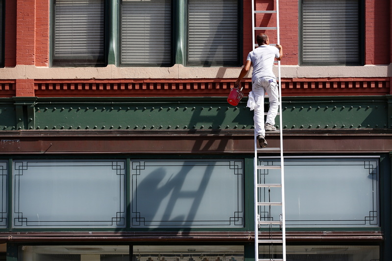 A painters shadow follows him on the wall, as he makes his way up a ladder on a building he is painting in downtown New Bedford, MA. PHOTO PETER PEREIRA