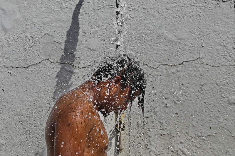 Mario Guerrero takes refuge from the heat under the outdoor shower on West Beach in New Bedford, MA. PHOTO PETER PEREIRA