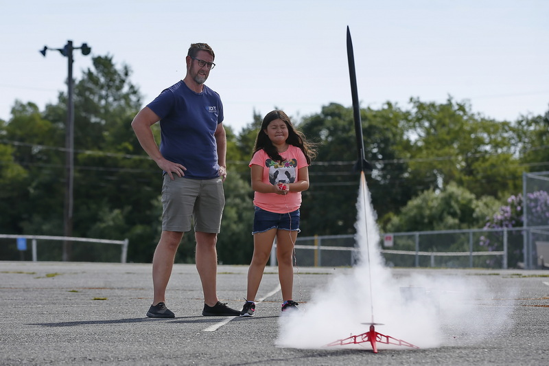 David Zwacki looks on as his daughter Cali Zwacki, 9, closes her eyes as she triggers the rocket launch at the DYAA field in Dartmouth, MA.  PHOTO PETER PEREIRA