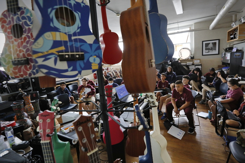 Colorful ukulele's hang on a rack, while students watch a documentary on different musical styles around the world in music class at the Global Learning Charter Public School in New Bedford, MA which is celebrating its 20th anniversary. PHOTO PETER PEREIRA