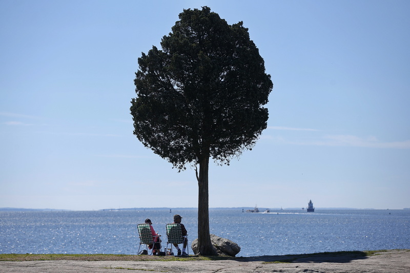 Two people sit under the solitary tree at Fort Phoenix in Fairhaven, MA enjoying the view and the weather. PHOTO PETER PEREIRA