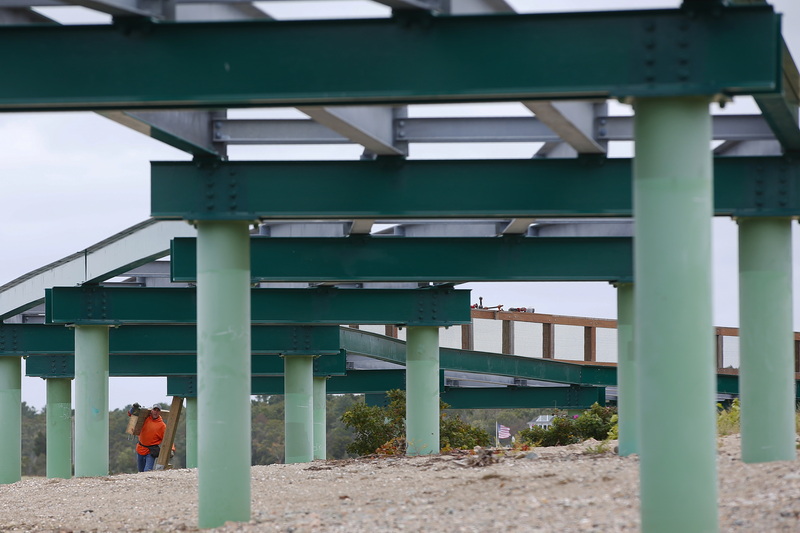 Billy Phillips of D. W. White carries a section of the guardrail being installed at the elevated bike path crossing Mattapoisett River and Eel Pond in Mattapoisett, MA whose planks had to be removed after warping. PHOTO PETER PEREIRA