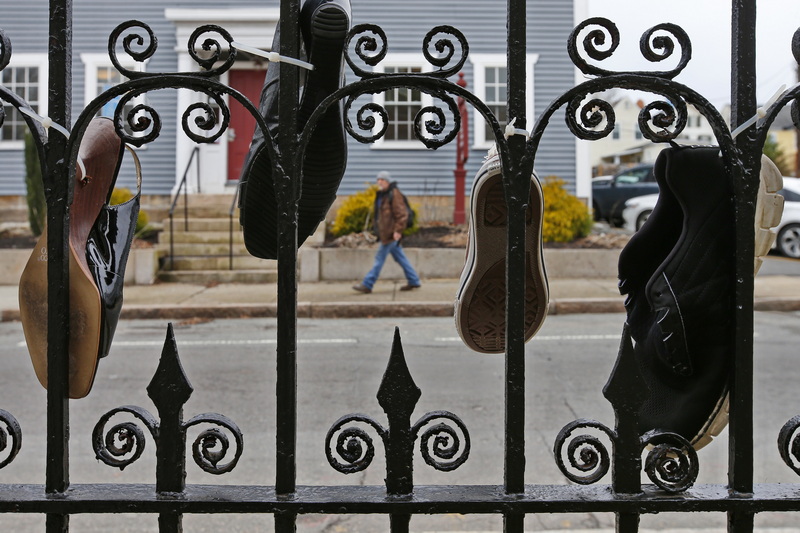 A man walks past shoes hanging on the fence in front of the YWCA on S. 6th Street in  New Bedford, MA which is hosting a discussion on human trafficking on January 26th, entitled In Their Shoes.  PHOTO PETER PEREIRA