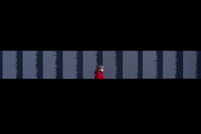 A woman walks past the names of soldiers killed in the Vietnam War inscribed on the stones of the Vietnam Memorial Wall at Bicentennial Park in Fall River, MA. This wall is an 80% replica of the Vietnam Veterans Memorial Wall found in Washington D.C. PHOTO PETER PEREIRA