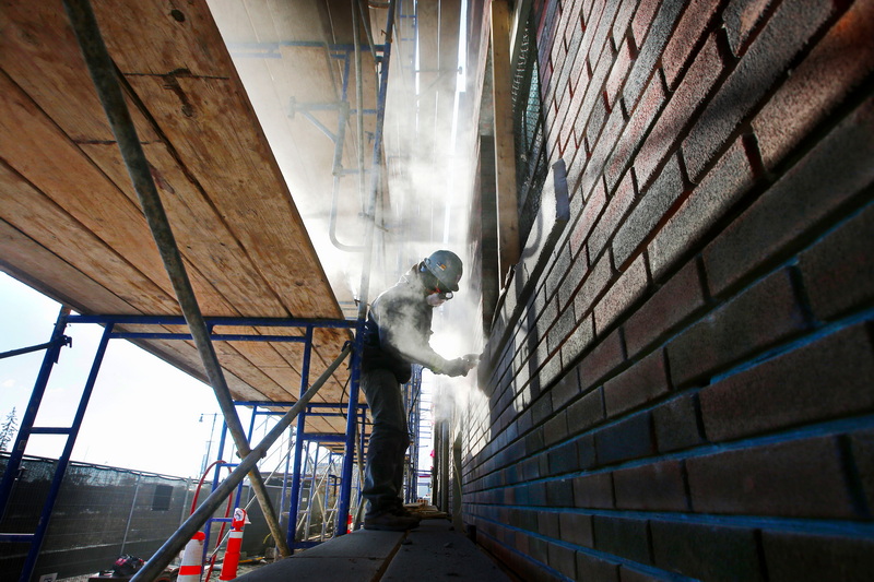 Jonathan Garcia is enveloped in his work as he repoints the brickwork of the former National Club at the bottom of Union Street in New Bedford, MA now being developed into residences.  PHOTO PETER PEREIRA