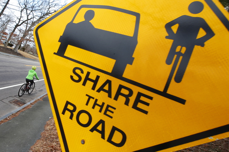 A woman rides her bicycle up Old Westport Road in Dartmouth, MA past a Share the Road traffic sign.  PHOTO PETER PEREIRA