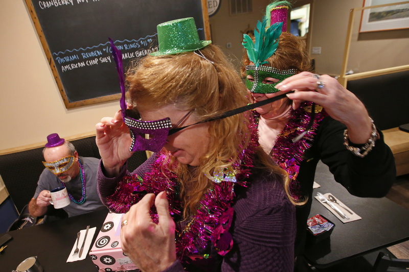 Fred Pinto enjoys his coffee as Joyce Iddon helps fellow St. Mary's Church parishioner Kathy Wunschel with her mask, before eating their annual Mardi Gras breakfast at Little Village Caf in Fairhaven, MA which they have done for the last eight years.  PHOTO PETER PEREIRA