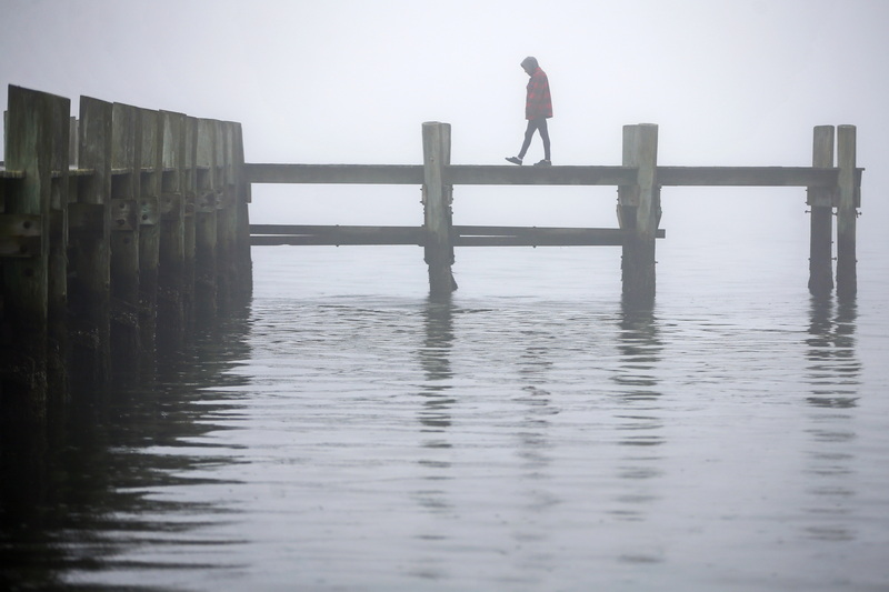 A woman walks across the dock in the south end of New Bedford on a foggy morning.