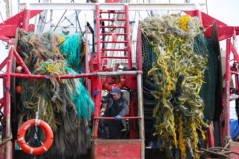 Pedro Cura squeezes between the two drums holding the nets of his fishing boat Fisherman, as he prepares to replace the steel cables of his boat docked in New Bedford, MA. PHOTO PETER PEREIRA