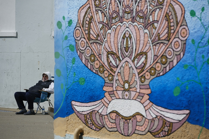 Bill Hinchliffe takes a seat next to a colorful painted shell mural, to enjoy the sun on West Beach in New Bedford, MA. PHOTO PETER PEREIRA