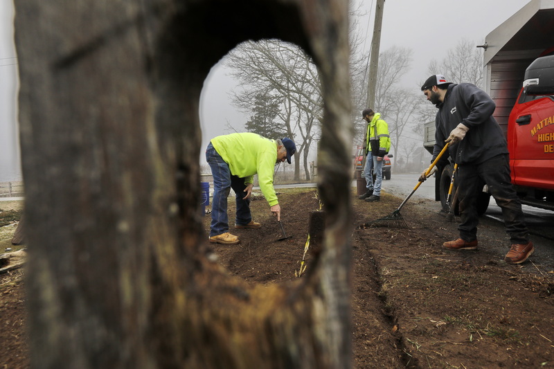 Fred Chaples, Freemin Bauer and Tom Bosworth of the Mattapoisett Highway Department, do some spring cleaning as seen through a hole in an old fence lining Shipyard Park in Mattapoisett, MA where whaling ships were once built.  PHOTO PETER PEREIRA