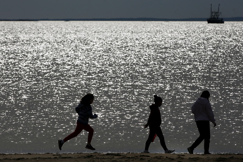 A fishing boat returns to port in the distance as Haiden McFadden fifth graders look for marine life on East Beach in New Bedford, MA as part of their weekly Sea Lab studies. PHOTO PETER PEREIRA