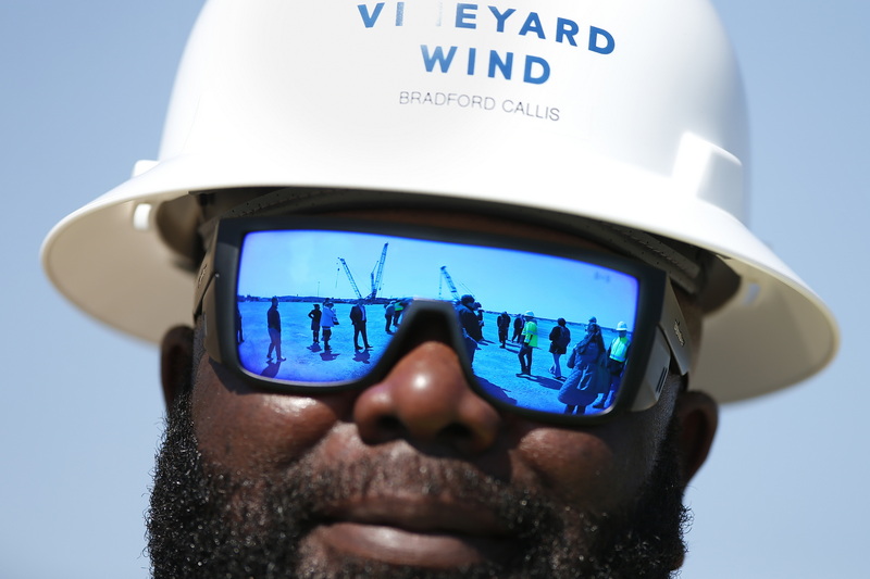 Members of the One SouthCoast Chamber, and the cranes being built in the background, are reflected off the safety glasses worn by Vineyard Wind Safety Advisor, Brad Callis, during the Chamber's visit to the New Bedford Marine Commerce Terminal to check on progress. PHOTO PETER PEREIRA