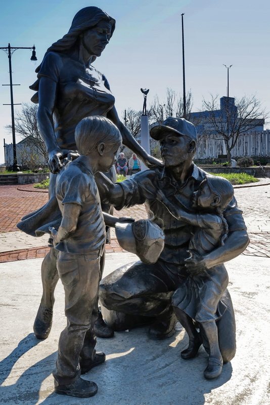 David Guilbert and his wife Giselle Guilbert are seen in a gap in the fisherman statue on New Bedford's waterfront, while taking a break after doing some gardening in the small park behind the statue. PHOTO PETER PEREIRA