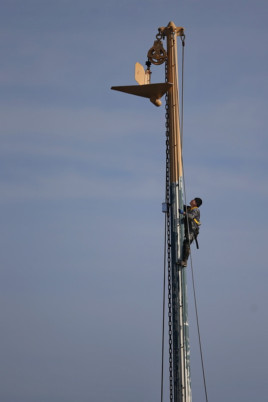 A painter scales a fishing boat's outrigger he is painting docked in New Bedford, MA. PHOTO PETER PEREIRA