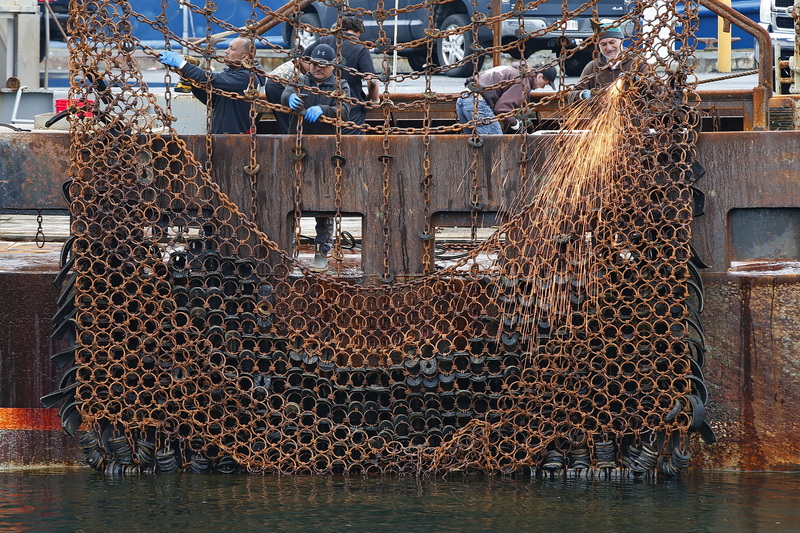 Fishermen make repairs to the dredges of a scalloper docked in New Bedford, MA. PHOTO PETER PEREIRA