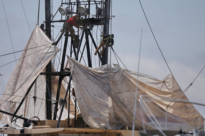 Workers remove the rust from a fishing boat being prepared to get painted, docked at Fleet Marina on Pope's Island in New Bedford, MA. PHOTO PETER PEREIRA