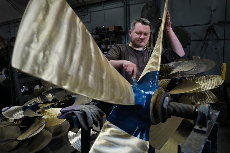 Andy Limantas paints the hub with the trademark color as he puts the finishing touches on the sixty-three-inch propeller of a scalloper fishing boat he just finished repairing at Fleet Propeller in Fairhaven, MA. PHOTO PETER PEREIRA