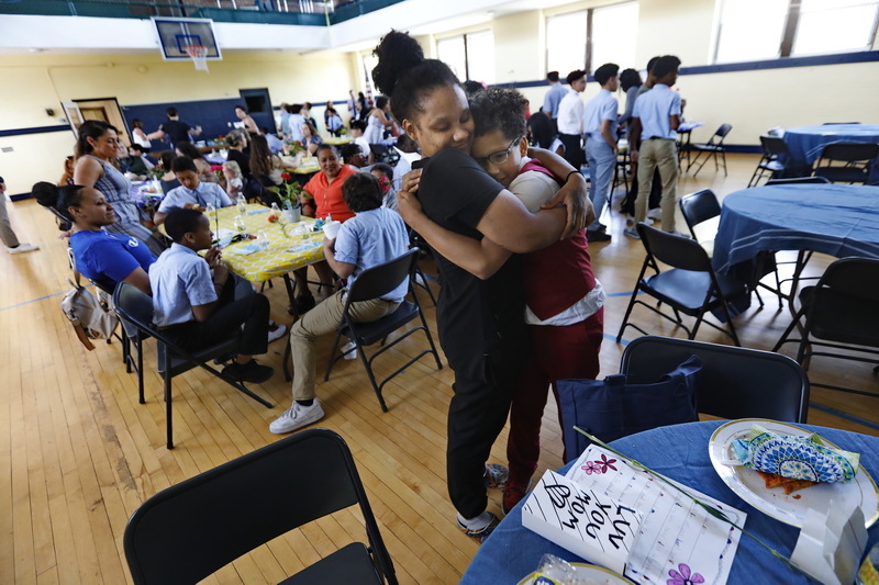 Carla Amado is overcome with emotion and hugs her son Aiden Amado, 11, after opening the gift he made for her (seen on table) during the Nativity Preparatory School Mother's Day lunch held in the school's gymnasium in New Bedford, MA. PHOTO PETER PEREIRA