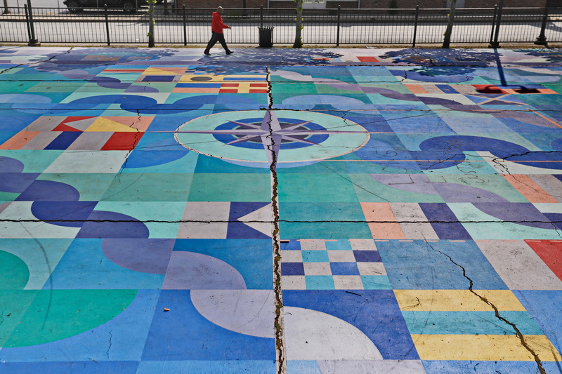 A man walks past the colorful basketball court at Clasky Common Park in New Bedford, MA. PHOTO PETER PEREIRA