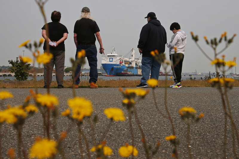 People look from the hurricane barrier as a ship carrying wind turbine blades for Vineyard Wind arrives at New Bedford Marine Commerce Terminal. PHOTO PETER PEREIRA