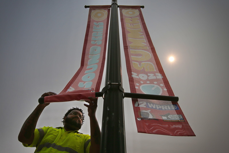 Carlos Medina insalls the Summer Sound Series banners on both sides of a light pole lining Route 18 in New Bedford, MA. PHOTO PETER PEREIRA