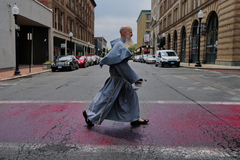 Franciscan Friar John makes his way across Pleasant Street in downtown New Bedford from Our Lady's Chapel to the vehicle the friars use as they prepare for the procession on Sunday between the chapel and Our Lady of Guadalupe on County Street in New Bedford, MA. PHOTO PETER PEREIRA