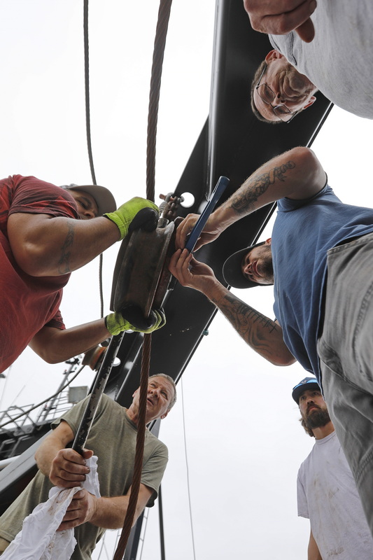 Fishermen from the scalloper American Viking make repairs to the bearings of the pulley used to hoist the dredges when they are out at sea, while docked at State Pier in New Bedford. PHOTO PETER PEREIRA