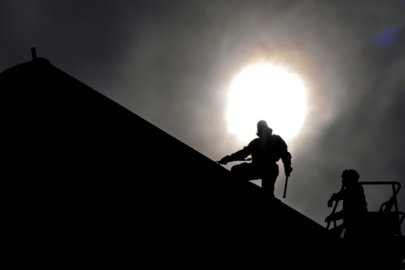 Men in hazmat suits remove the roof from the former Market Ministries Shelter on 8th Street in New Bedford, MA as the sun rises on a hazy morning. PHOTO PETER PEREIRA