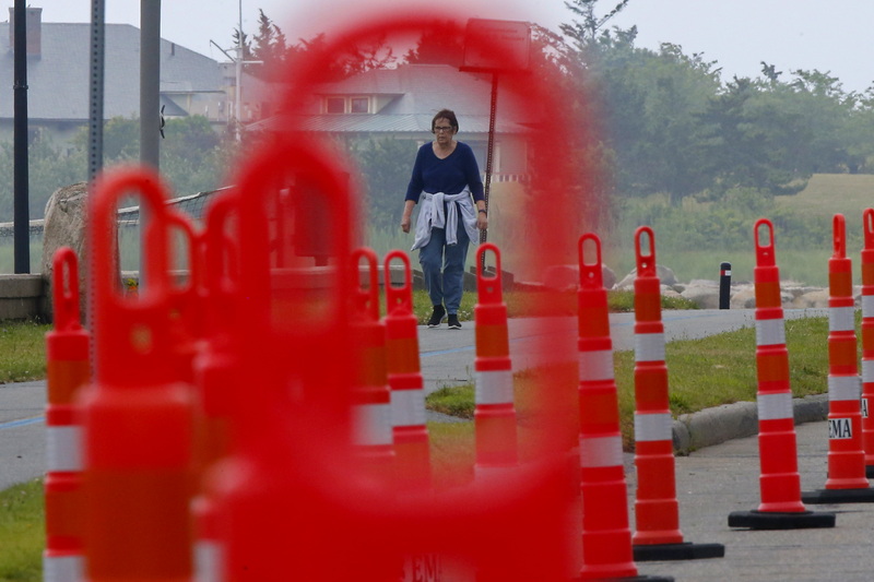 A woman walks dont the Blue Lane walk path next to East Beach in New Bedford, MA as seen through the cones lining East Rodney French Boulevard in preparation for the beach season. PHOTO PETER PEREIRA