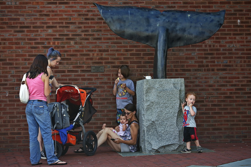 A family takes a break from the sun under the overhang protecting the iconic whale tail sculpture at the New Bedford Whaling Museum, MA. PHOTO PETER PEREIRA