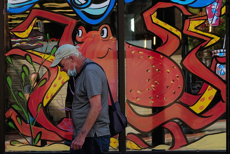 A man is captured by an octopus painted on the windows of Arpeggio Cafe in downtown New Bedford, MA. PHOTO PETER PEREIRA