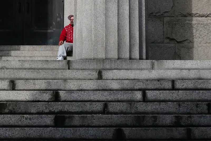 A man takes shelter from the rain behind one of the large columns that face the New Bedford public library on William Street. PHOTO PETER PEREIRA