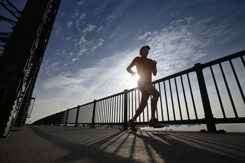 The rising sun peeks behind Scott Anderson as he crosses the Fairhaven bridge during an early morning run. PHOTO PETER PEREIRA