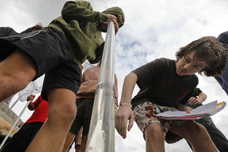 Old Rochester Regional High School student Cody Barrows looks into the column of water while Dominic Hurley reads the height as they and fellow Marine Biology students take a water clarity test during their visit to Pine Island Pond in Mattapoisett, MA.  PHOTO PETER PEREIRA