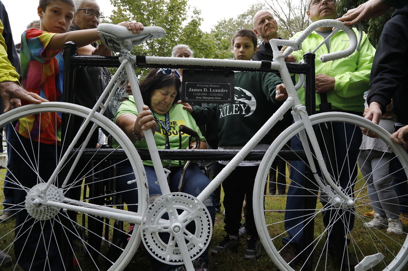 Friends and family offer Ruth Leandre her support as she breaks down upon touching the 'ghost bike' sculpture installed in front of the Acushnet Council on Aging where her son James Leandre was killed by a truck while riding his bicycle at the same location in December of last year.  PHOTO PETER PEREIRA