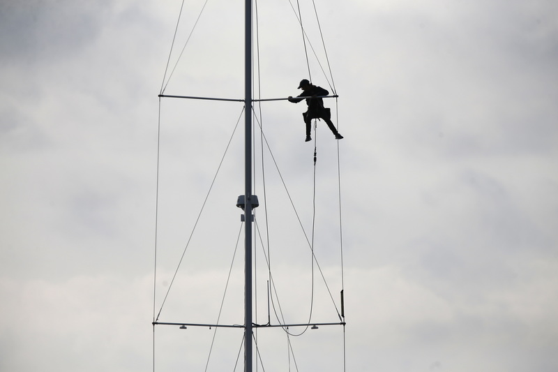 A rigger makes adjustments to a sailboat's mast docked in Padanaram harbor in Dartmouth, MA. PHOTO PETER PEREIRA