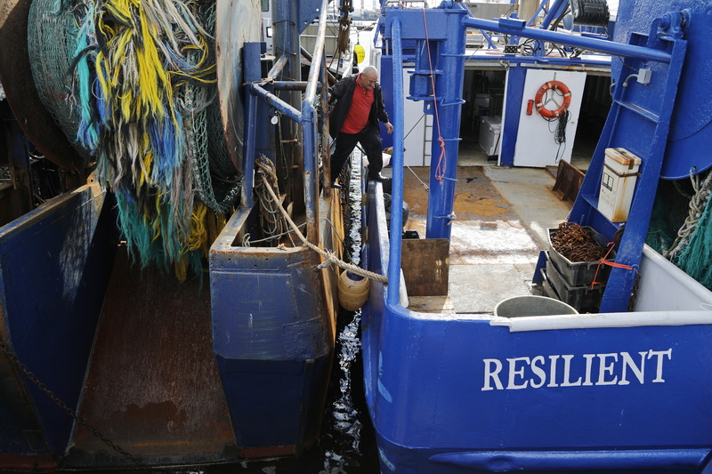 Victor Vidreiro, cook of the fishing boat Sao Marcos, crosses across onto the fishing boat Resilient before stepping onto the dock in New Bedford, MA upon arriving from a fishing trip. PHOTO PETER PEREIRA