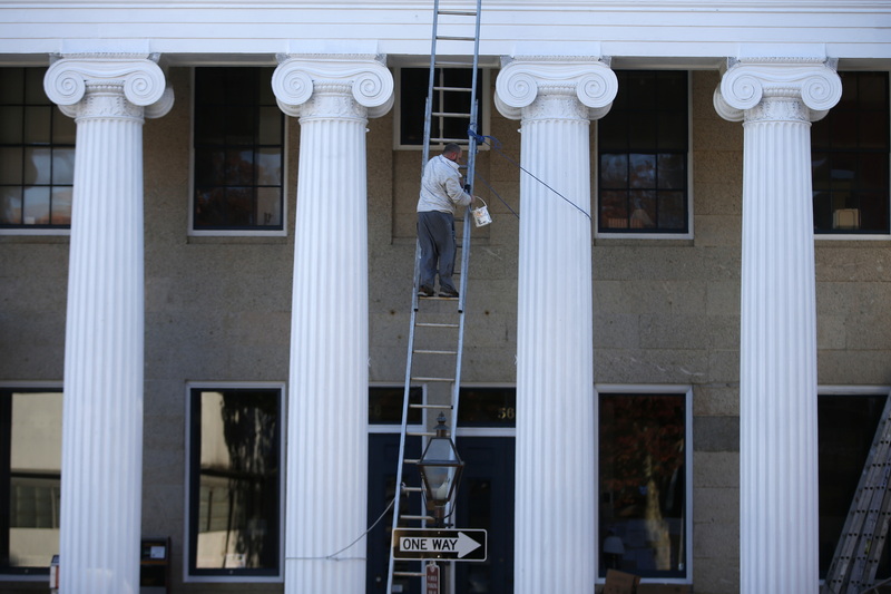 A painter makes his way slowly down the ladder between the iconic colonnade of the Best Banc & Co building on William Street in downtown New Bedford, MA. PHOTO PETER PEREIRA