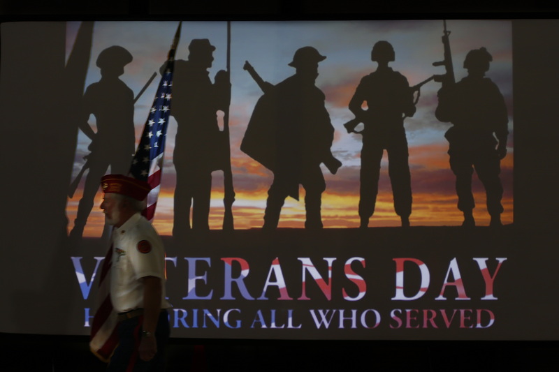 Marine Corps veteran Edward Cabral walks past the slide honoring veterans on his way to post the colors during the Veterans Day assembly at the Roosevelt Middle school in New Bedford, MA.  PHOTO PETER PEREIRA