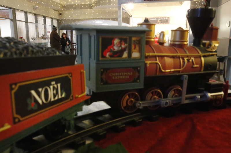 Two people waiting for coffee seem to be waiting to board the Christmas Express model train on display at the DeMello International Center in downtown New Bedford, MA. PHOTO PETER PEREIRA