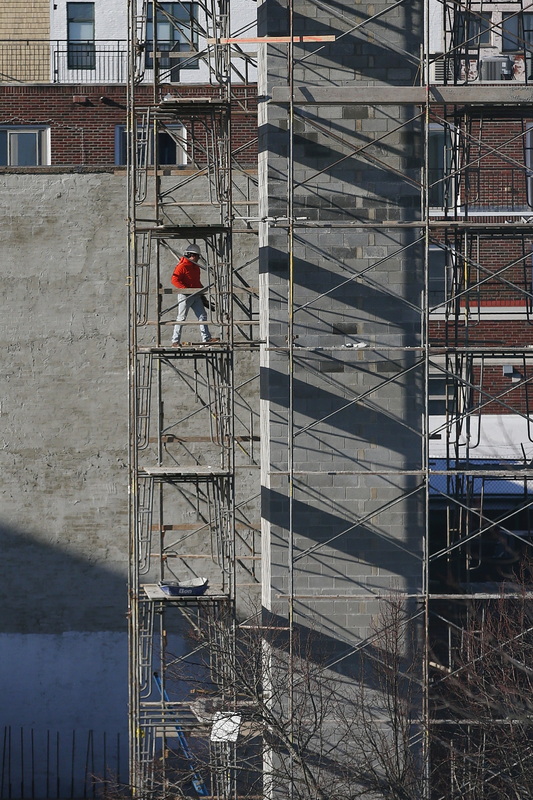 A man scales the staging of the elevator shaft being constructed for a residential building in downtown New Bedford, MA. PHOTO PETER PEREIRA