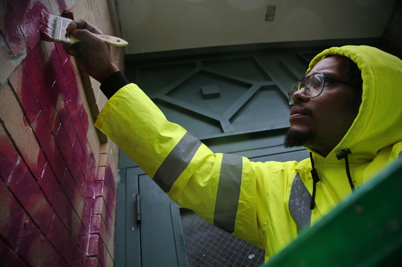 Aaron Adams of New Bedford DPI uses a solvent to remove graffiti someone wrote on the entrance to a business on Union Street in downtown New Bedford, MA. PHOTO PETER PEREIRA