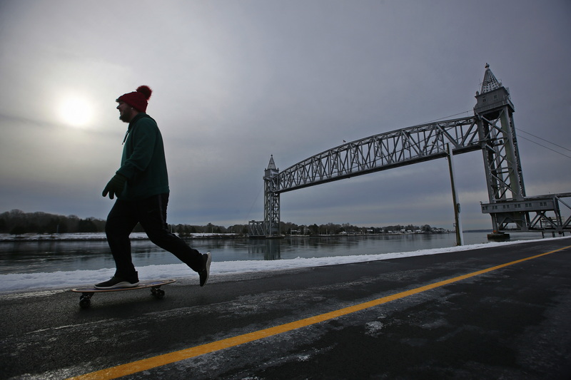 A man rides his skateboard along the Cape Cold canal in Buzzards Bay, MA in the background the iconic rail bridge..  PHOTO PETER PEREIRA