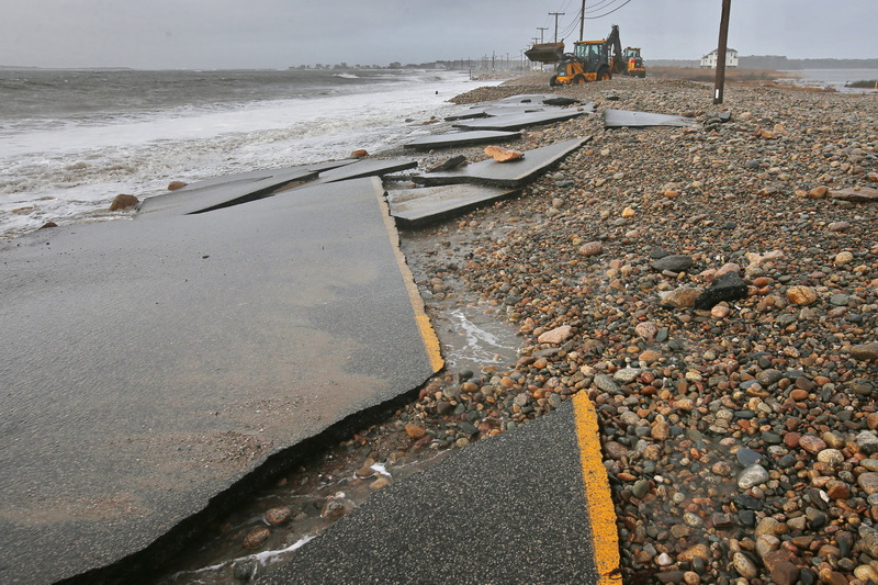 The remnants of East Beach Road in Westport, MA are seen in the foreground as Westport Highway Department workers remove rocks with bulldozers after heavy overnight winds and surf battered the coastline. PHOTO PETER PEREIRA