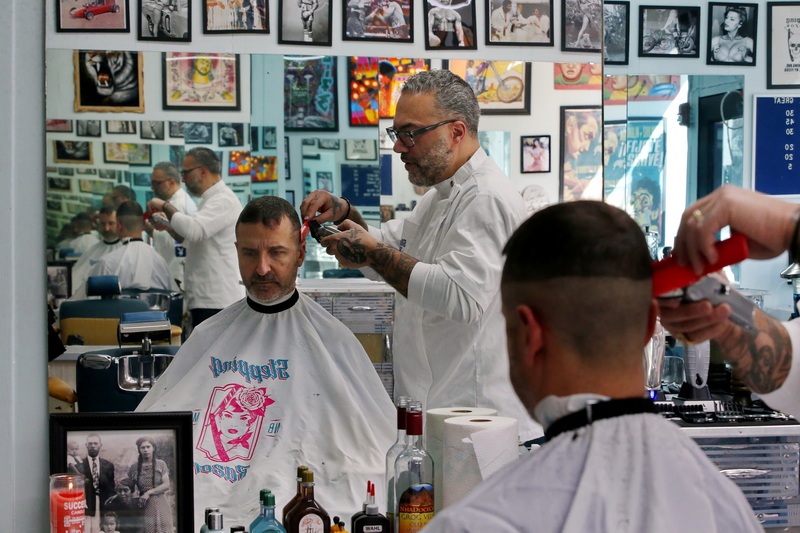 Danny Baptista, owner, is reflected in the mirror in the background as he gives Robert Serpa a haircut at his just opened Stepping Razor barber shop on Union Street in New Bedford at the former Not Your Fathers Moustache location.  Mr. Serpa is the first customer at this is a companion barber shop to Stepping Razor in Brooklyn, New York.  PHOTO PETER PEREIRA